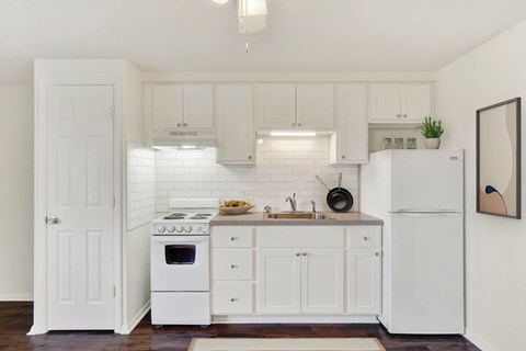 A white kitchen with a refrigerator, oven, and sink.