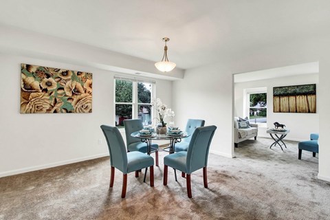 A dining room with a table set for two and a painting on the wall.
