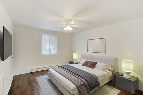 A bedroom with a bed, nightstand, and a ceiling fan.