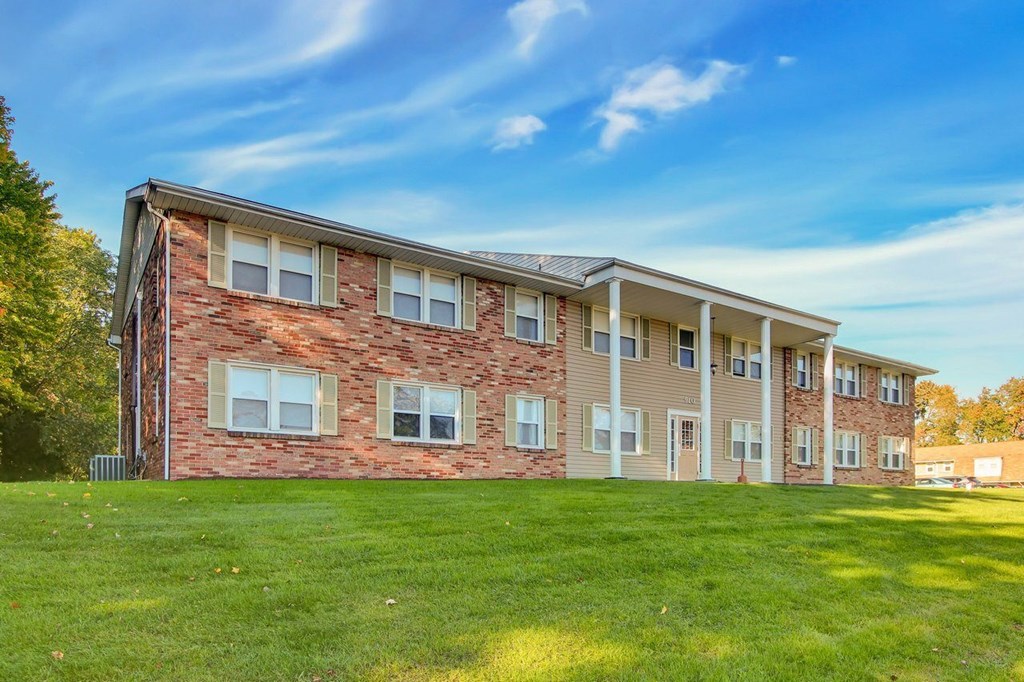 A large brick building with a green lawn in front.