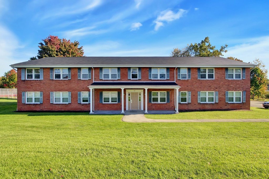 A red brick building with a green lawn in front.