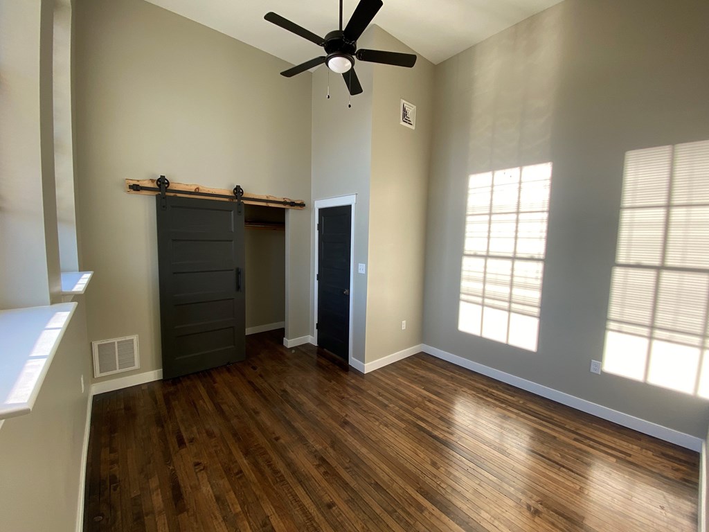 A room with a ceiling fan and wooden floors.