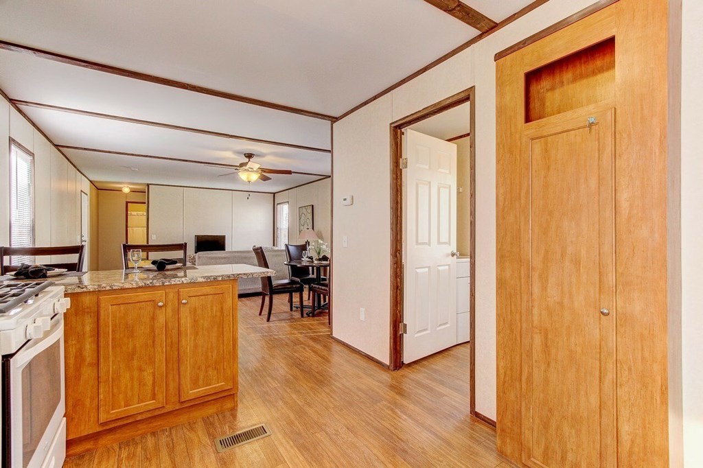 A kitchen with wooden floors and a white ceiling fan.