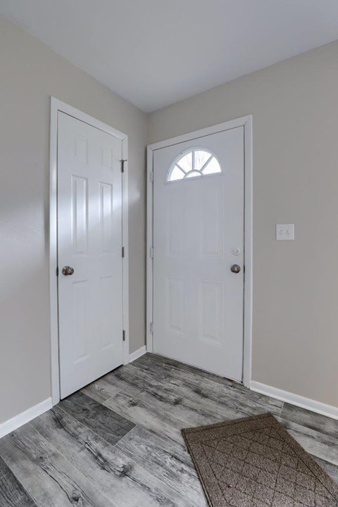 A hallway with two white doors and a brown rug on the floor.