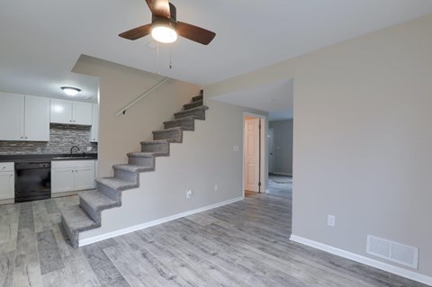 A room with a staircase and a ceiling fan.
