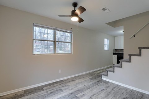 A room with a staircase on the right and a window on the left.