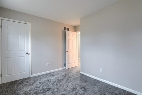 A room with a carpeted floor and a white door.