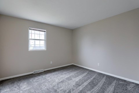 A room with a carpeted floor and a window.