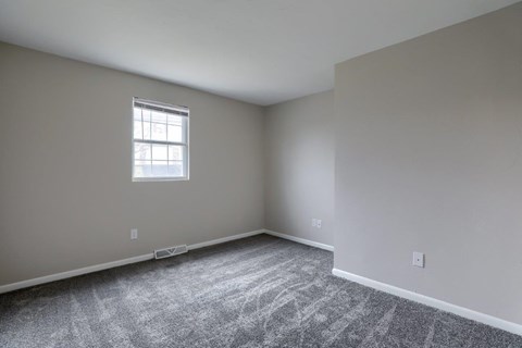 A room with a window and carpeted floor.