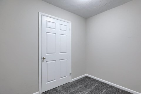 A white door is in a room with a grey carpet.