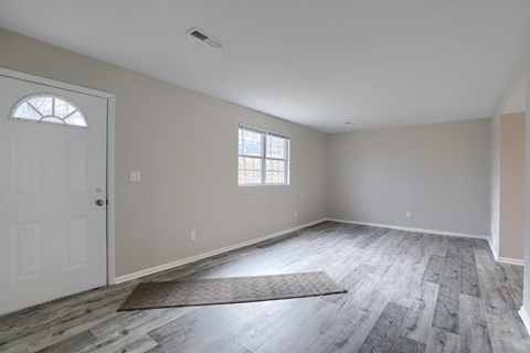 A room with a door, window, and a rug on the floor.