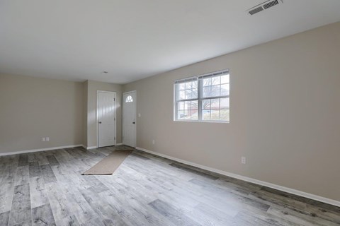 A room with a window and a rug on the floor.