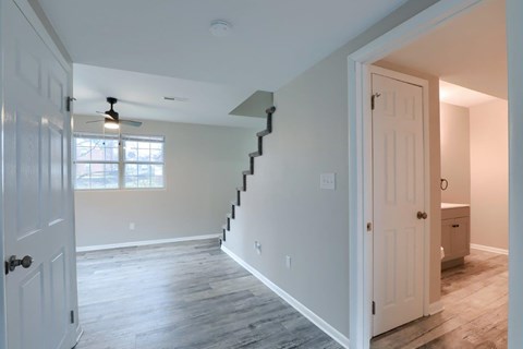 A white door is open to a hallway with a staircase.