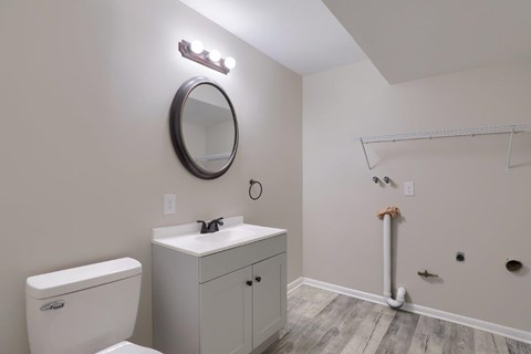 A bathroom with a toilet, sink, and mirror.