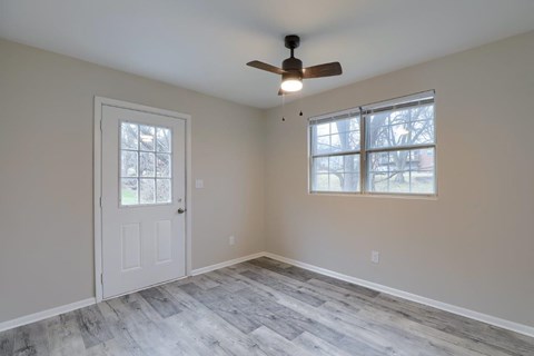 A room with a ceiling fan and a window with a view of trees.