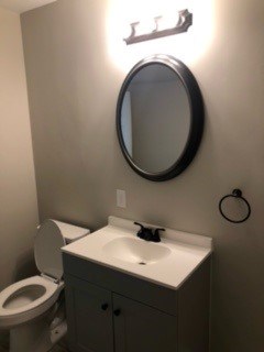 A bathroom with a toilet, sink and mirror.