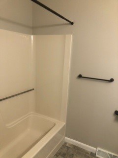 A white bathroom with a tub and a towel bar.