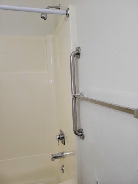 A white shower door with a silver handle.