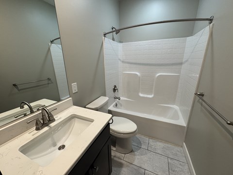 A white toilet is in a bathroom with a white shower curtain.
