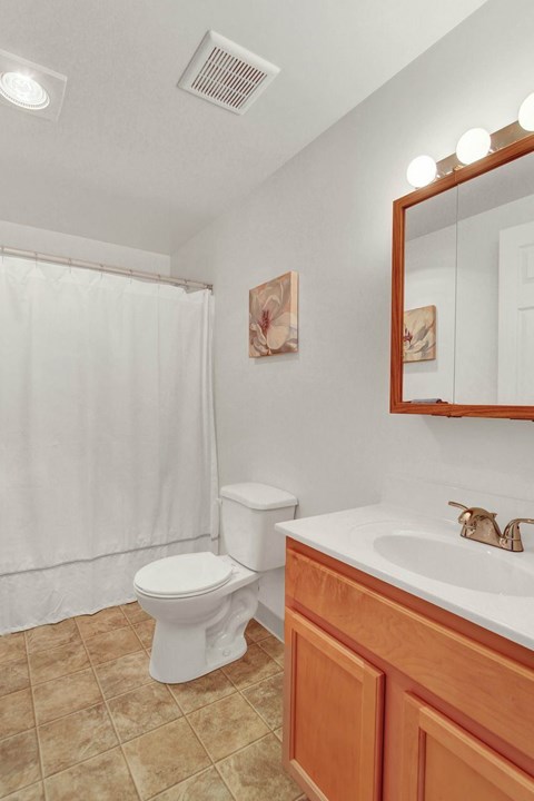 A white toilet sits in a bathroom next to a sink.