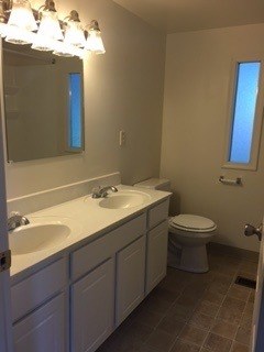 A bathroom with a toilet, sink and mirror.