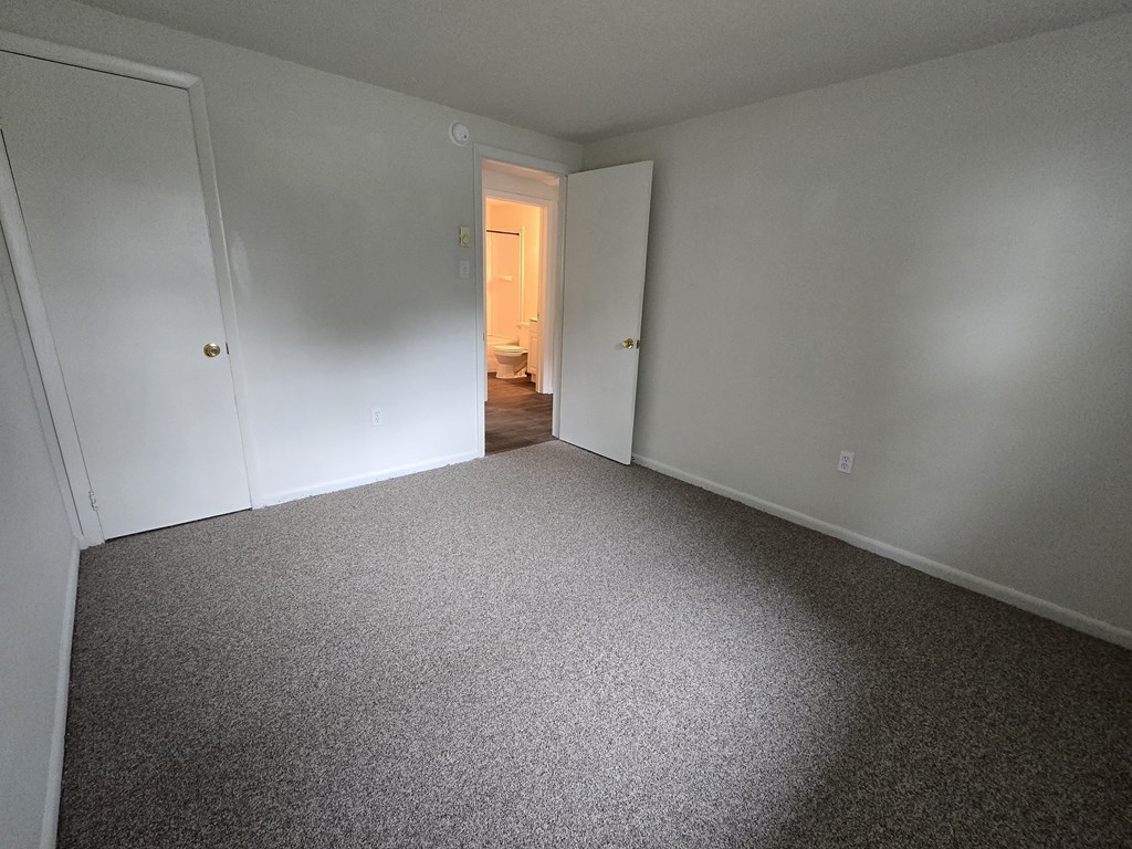 A room with a carpeted floor and two doors.