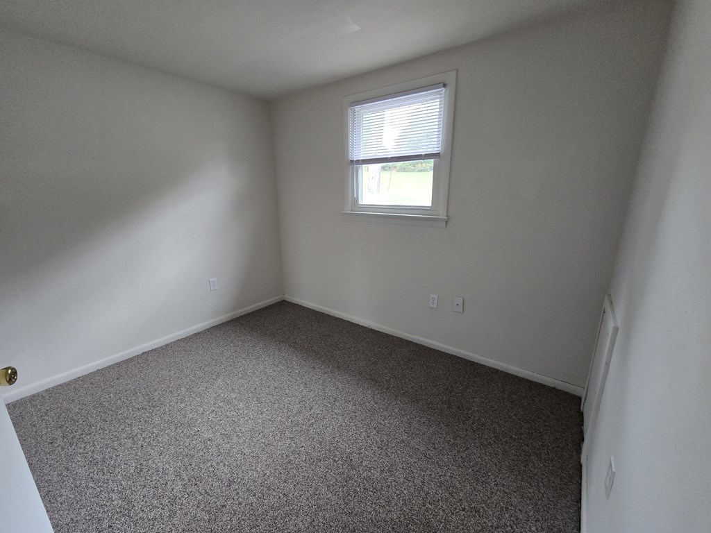 A small room with a carpeted floor and a window.