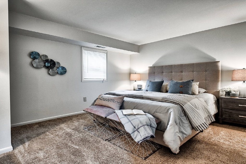 A bedroom with a large bed and a decorative wall piece.