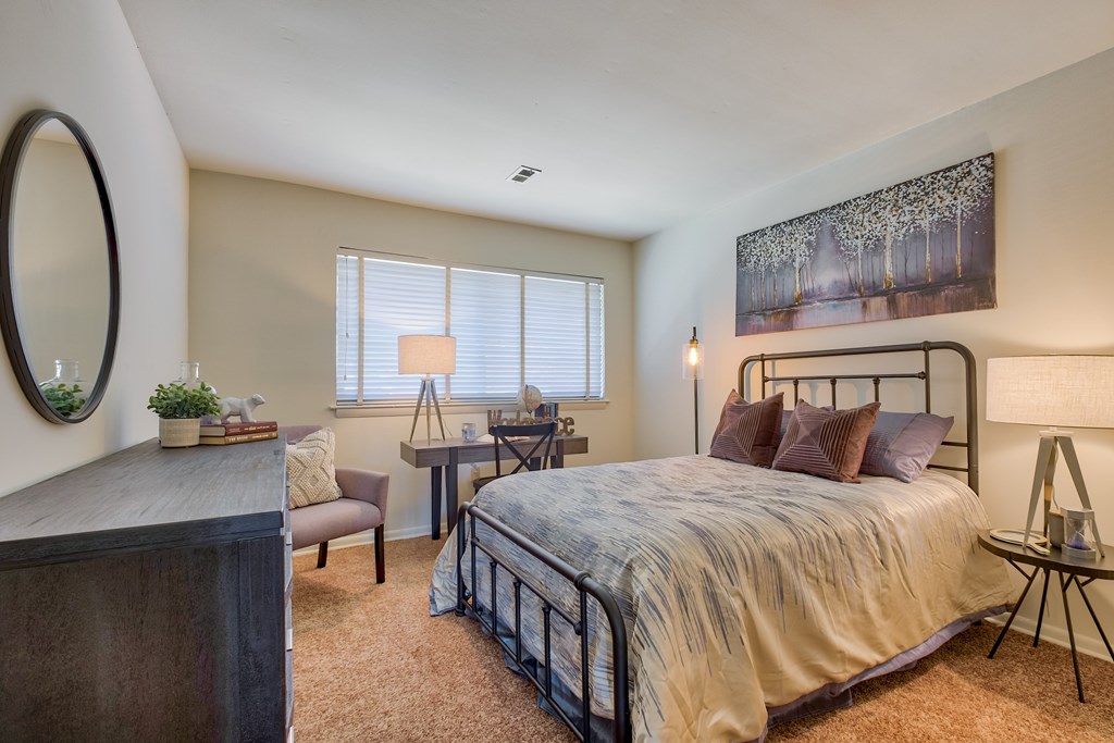 A bedroom with a bed, chair, and a table.