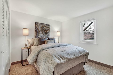 A bedroom with a large bed and two lamps on either side of the bed.