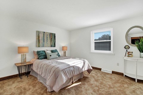A bedroom with a bed, nightstand, and a painting on the wall.
