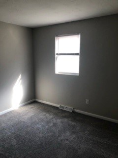 A room with a window and a carpeted floor.