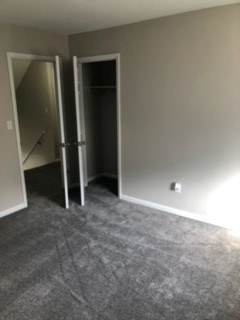 A room with a carpeted floor and two doors, one of which is open.