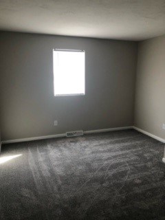 A room with a window and carpet on the floor.