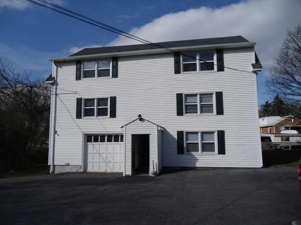 A white two-story house with a garage on the ground floor.