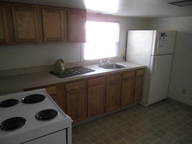 A kitchen with a white stove and wooden cabinets.
