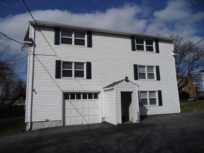 A white house with a garage door and a small porch.