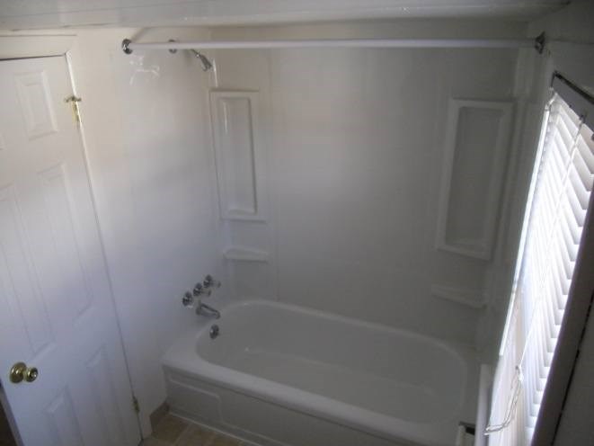 A white bathroom with a tub and a door.