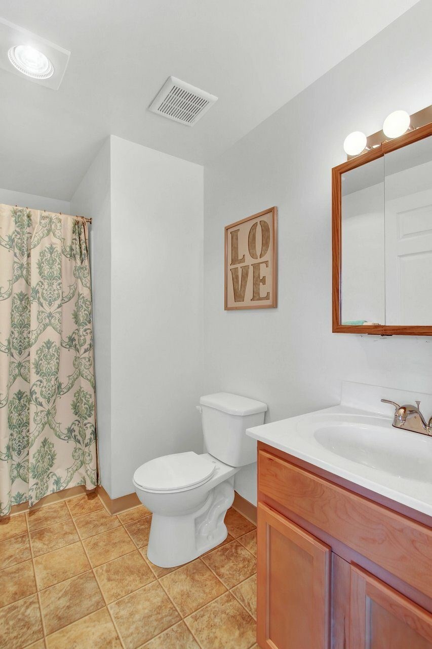 A bathroom with a toilet, sink, and mirror.