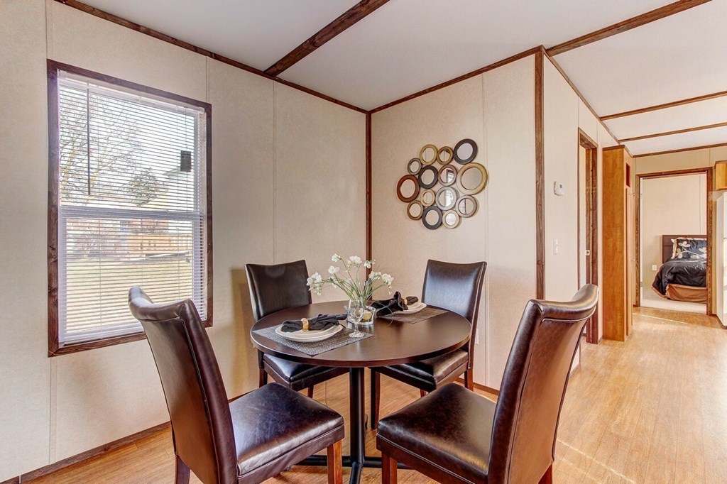 A dining room with a table set for two and a decorative wall piece.