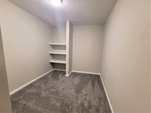A room with a carpeted floor and a staircase.