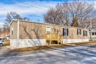 A small building with a porch is surrounded by a parking lot.