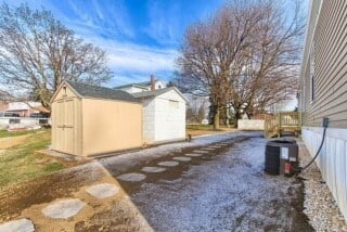 A driveway with a shed and a house in the background.