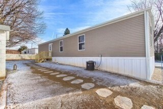 A mobile home with a white fence and a brown roof.