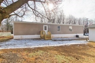 A two-story house with a garage is surrounded by a snowy landscape.