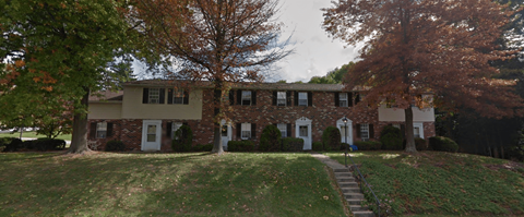 A two-story house with a front porch and a staircase leading to the front door.