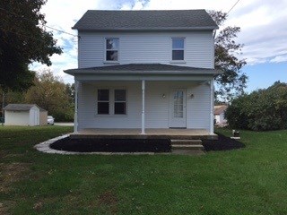 A two story white house with a black roof.