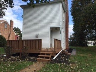 A small white building with a brown deck in front.