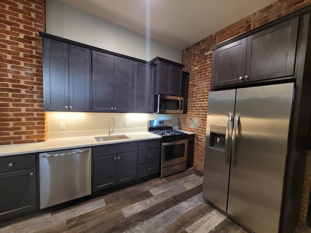 A kitchen with a refrigerator, sink, and oven.