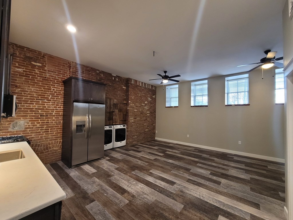 A kitchen with a refrigerator and a ceiling fan.